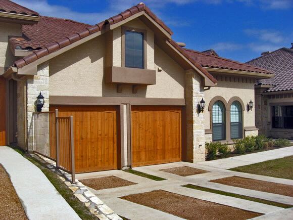 a condo exterior with wooden garage doors and stylized driveways at Escondera Condominiums in TX