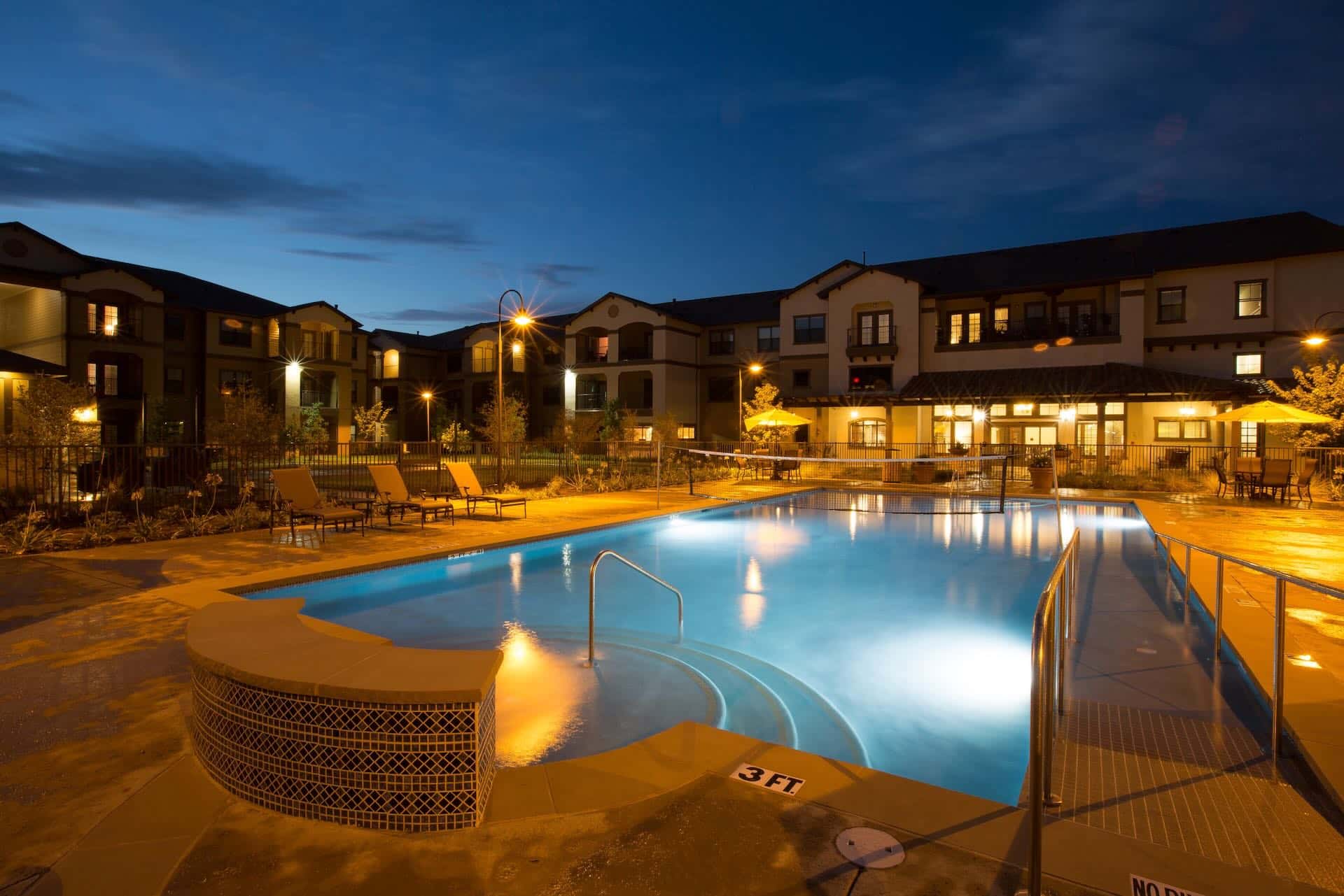 the outdoor pool lit up at night at Mariposa Apartment Homes Elk Drive in Texas