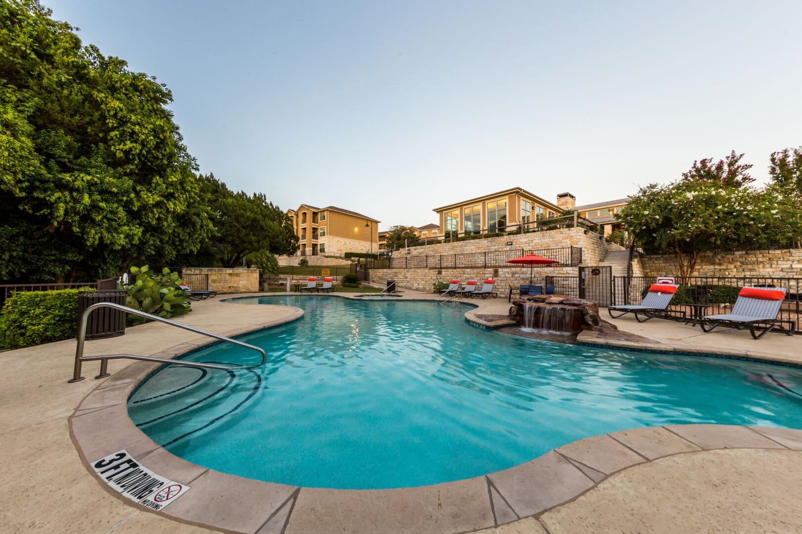 a curvy outdoor pool with waterfall feature at Marquis at Canyon Ridge in TX